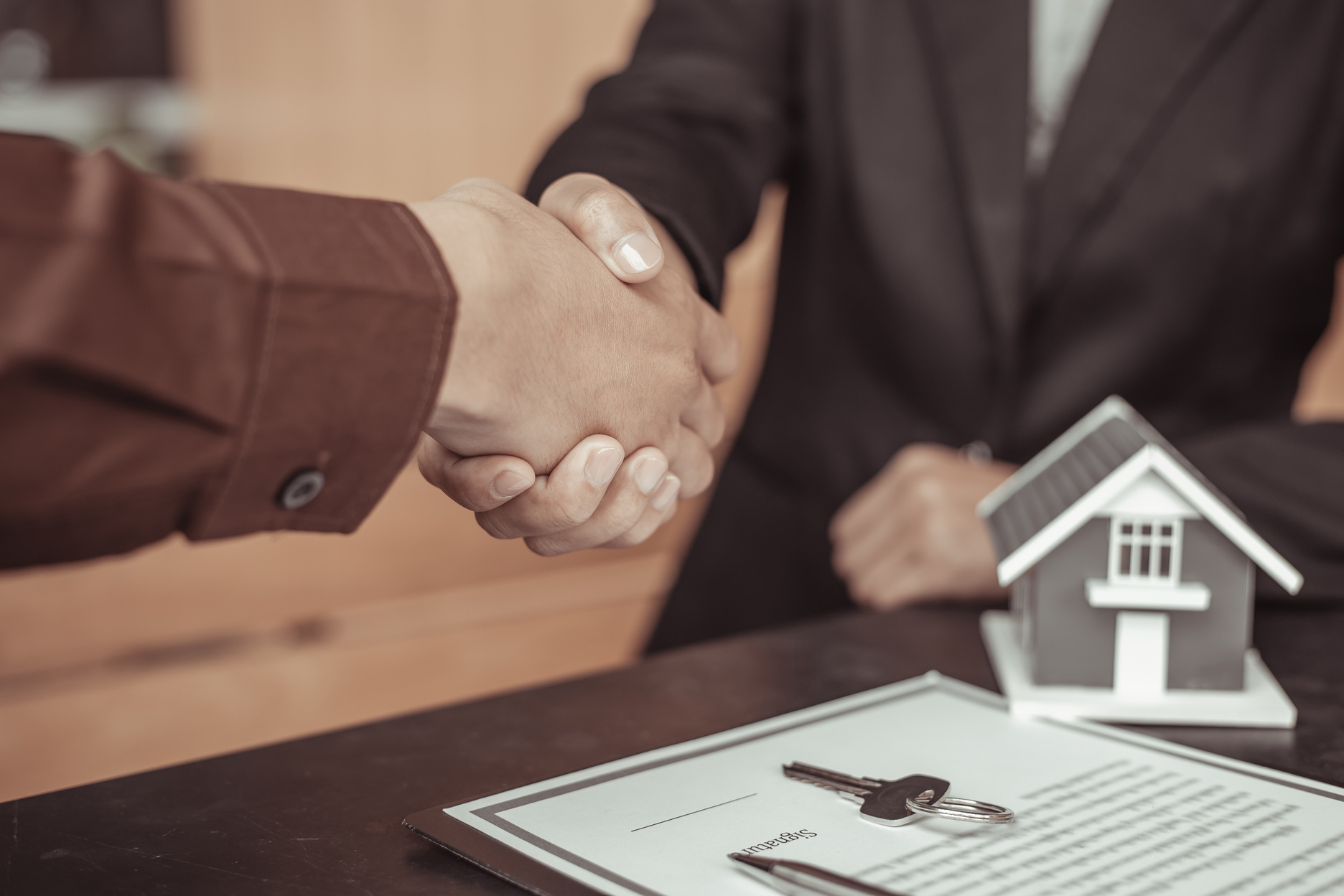 Real Estate Agent and Client Doing Handshake Above the Contract